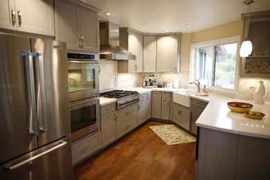 Mid-sized country l-shaped medium tone wood floor and brown floor kitchen pantry photo in San Diego with a farmhouse sink, shaker cabinets, gray cabinets, marble countertops, beige backsplash, stainless steel appliances and a peninsula