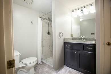 Example of a mid-sized transitional 3/4 gray tile and cement tile ceramic tile alcove shower design in Louisville with an undermount sink, furniture-like cabinets, dark wood cabinets, granite countertops, a two-piece toilet and white walls