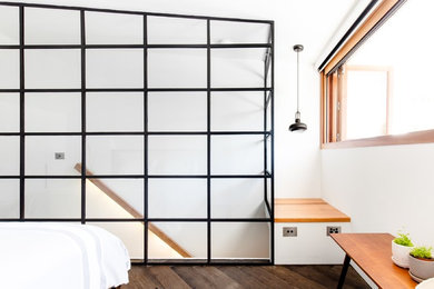 シドニーにある小さなインダストリアルスタイルのおしゃれなロフト寝室 (白い壁、暖炉なし、茶色い床) のインテリア