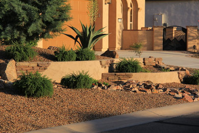Photo of a mid-sized mediterranean front yard full sun xeriscape for summer in Phoenix with gravel.