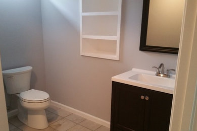 Example of a small classic 3/4 ceramic tile and beige floor corner shower design in Philadelphia with shaker cabinets, black cabinets, a two-piece toilet, gray walls, an integrated sink, quartzite countertops and a hinged shower door