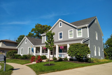 Photo of a medium sized and gey classic two floor detached house in Milwaukee with wood cladding, a pitched roof, a shingle roof, a grey roof and board and batten cladding.
