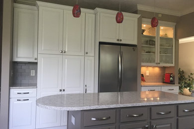 This is an example of a mid-sized transitional l-shaped kitchen in Indianapolis with an undermount sink, raised-panel cabinets, white cabinets, quartz benchtops, grey splashback, porcelain splashback, ceramic floors and with island.