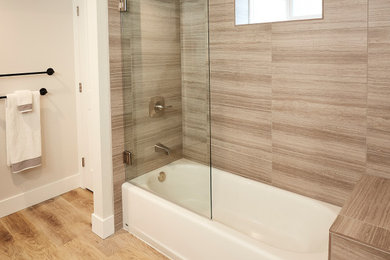 Example of a mid-sized trendy 3/4 gray tile and porcelain tile alcove bathtub design in Seattle with solid surface countertops, a hinged shower door and a freestanding vanity
