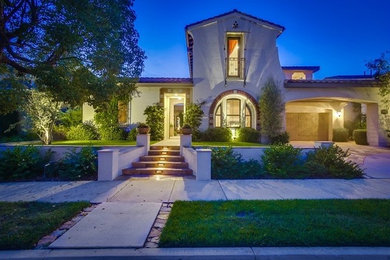 Inspiration for a large mediterranean white two-story stucco exterior home remodel in San Diego with a tile roof