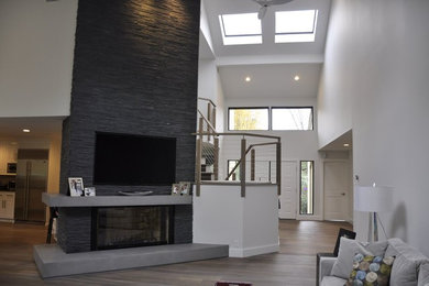 Inspiration for a contemporary open concept light wood floor living room remodel in New York with white walls, a standard fireplace, a stone fireplace and a wall-mounted tv