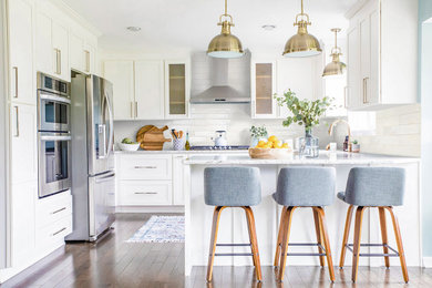 Kitchen - mid-sized contemporary u-shaped medium tone wood floor and brown floor kitchen idea in DC Metro with a farmhouse sink, shaker cabinets, white cabinets, quartz countertops, white backsplash, subway tile backsplash, stainless steel appliances and white countertops