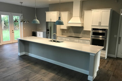 Large transitional galley ceramic tile and brown floor eat-in kitchen photo in Orlando with a single-bowl sink, shaker cabinets, white cabinets, stainless steel appliances and an island