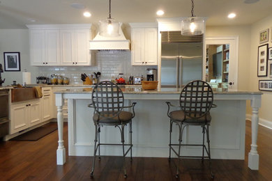 Open concept kitchen - large transitional u-shaped dark wood floor open concept kitchen idea in Raleigh with a farmhouse sink, recessed-panel cabinets, white cabinets, granite countertops, white backsplash, subway tile backsplash, stainless steel appliances and an island