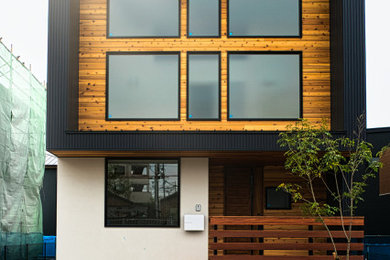 Esempio della facciata di una casa piccola nera moderna a due piani con rivestimento in legno, copertura in metallo o lamiera, tetto nero e con scandole