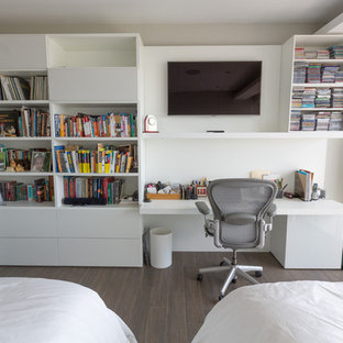 This is an example of a medium sized modern study in Miami with white walls, medium hardwood flooring, a built-in desk and brown floors.