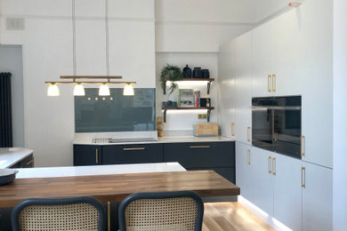 Idéer för ett mellanstort modernt vit kök, med en integrerad diskho, släta luckor, grå skåp, bänkskiva i kvartsit, blått stänkskydd, glaspanel som stänkskydd, rostfria vitvaror, mellanmörkt trägolv, en halv köksö och brunt golv