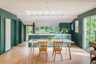 Great room - mid-sized contemporary light wood floor, brown floor and exposed beam great room idea in London with green walls