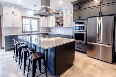 Example of a large transitional l-shaped concrete floor eat-in kitchen design in Minneapolis with an undermount sink, shaker cabinets, quartz countertops, white backsplash, subway tile backsplash, stainless steel appliances, an island and white countertops
