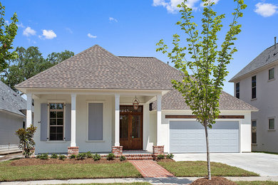Example of a mid-sized arts and crafts white one-story concrete fiberboard exterior home design in New Orleans with a hip roof