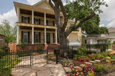 Example of a mid-sized ornate yellow two-story mixed siding exterior home design in Houston