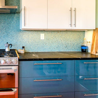 Cette photo montre une arrière-cuisine moderne en U de taille moyenne avec un placard à porte plane, des portes de placard blanches, une crédence bleue, un électroménager en acier inoxydable, un sol en linoléum, une péninsule, un sol orange, un évier posé, un plan de travail en granite, une crédence en mosaïque et un plan de travail noir.