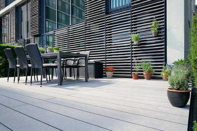 Diseño de terraza planta baja actual pequeña sin cubierta en patio lateral con jardín de macetas y barandilla de varios materiales