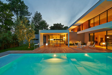 Idée de décoration pour une grande piscine arrière design rectangle avec une terrasse en bois.