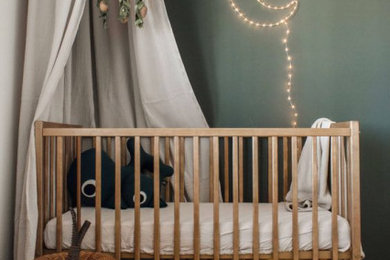Inspiration pour une chambre de bébé neutre rustique de taille moyenne avec un mur vert, parquet clair et un sol marron.