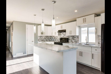 Inspiration for a mid-sized timeless u-shaped porcelain tile and brown floor eat-in kitchen remodel in Calgary with a drop-in sink, recessed-panel cabinets, white cabinets, laminate countertops, multicolored backsplash, matchstick tile backsplash, black appliances, an island and white countertops