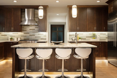 Open concept kitchen - large u-shaped light wood floor and brown floor open concept kitchen idea in Seattle with an undermount sink, shaker cabinets, dark wood cabinets, quartzite countertops, multicolored backsplash, glass tile backsplash, stainless steel appliances, an island and multicolored countertops