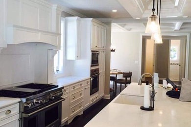 Open concept kitchen - mid-sized contemporary galley dark wood floor open concept kitchen idea in New York with a farmhouse sink, recessed-panel cabinets, white cabinets, granite countertops, stainless steel appliances and an island