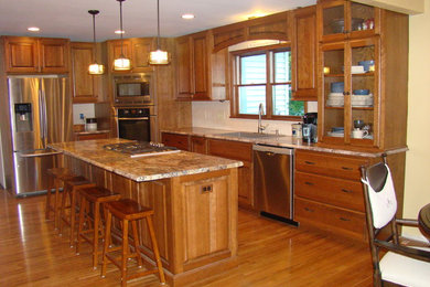 Inspiration for a mid-sized timeless l-shaped medium tone wood floor and brown floor eat-in kitchen remodel in Indianapolis with raised-panel cabinets, medium tone wood cabinets, granite countertops, white backsplash, an island, an undermount sink, subway tile backsplash and stainless steel appliances