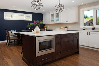 Mid-sized minimalist l-shaped dark wood floor and brown floor eat-in kitchen photo in Calgary with an undermount sink, shaker cabinets, white cabinets, quartz countertops, gray backsplash, stainless steel appliances, an island and white countertops