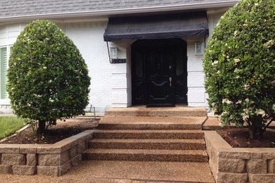 This is an example of a mid-sized modern courtyard driveway in Dallas with a retaining wall and concrete pavers.