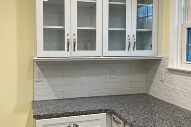 Example of a small u-shaped vinyl floor and brown floor kitchen design in Indianapolis with a double-bowl sink, shaker cabinets, white cabinets, granite countertops, white backsplash, subway tile backsplash, stainless steel appliances and multicolored countertops