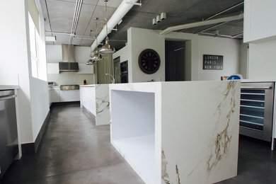 Large trendy l-shaped concrete floor open concept kitchen photo in Other with a double-bowl sink, recessed-panel cabinets, white cabinets, stainless steel appliances and two islands