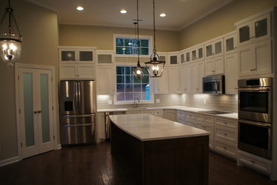 Example of a large transitional l-shaped dark wood floor open concept kitchen design in Charlotte with an undermount sink, shaker cabinets, white cabinets, quartz countertops, gray backsplash, ceramic backsplash, stainless steel appliances and an island