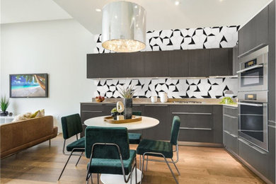 Inspiration for a large modern l-shaped medium tone wood floor, brown floor and vaulted ceiling eat-in kitchen remodel in Austin with an undermount sink, flat-panel cabinets, brown cabinets, laminate countertops, black backsplash, cement tile backsplash, stainless steel appliances, no island and beige countertops