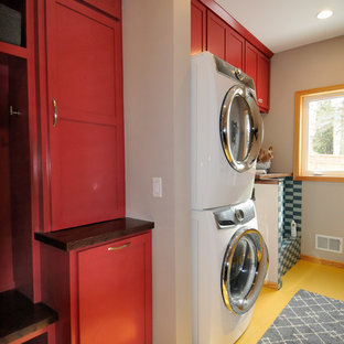 Design ideas for a medium sized contemporary single-wall utility room in Minneapolis with a submerged sink, shaker cabinets, red cabinets, wood worktops, beige walls, laminate floors, a stacked washer and dryer and yellow floors.