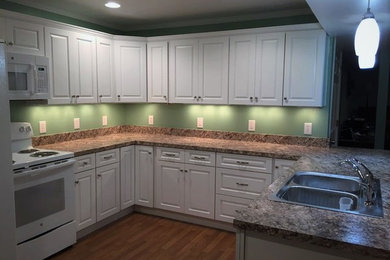 Small elegant u-shaped eat-in kitchen photo in DC Metro with a double-bowl sink, recessed-panel cabinets, white cabinets, laminate countertops, brown backsplash and white appliances