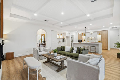 Large traditional open concept living room in Adelaide with a home bar, white walls, light hardwood floors, a standard fireplace, a stone fireplace surround and coffered.