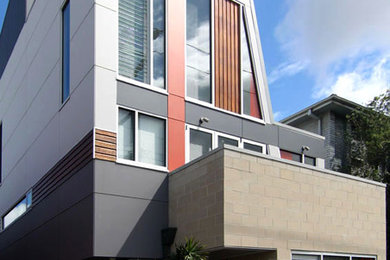 Photo of a small contemporary three-storey grey exterior in Other with concrete fiberboard siding.