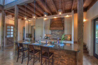Inspiration for a small rustic galley concrete floor open concept kitchen remodel in Austin with a farmhouse sink, shaker cabinets, gray cabinets, granite countertops, multicolored backsplash, brick backsplash, stainless steel appliances and an island