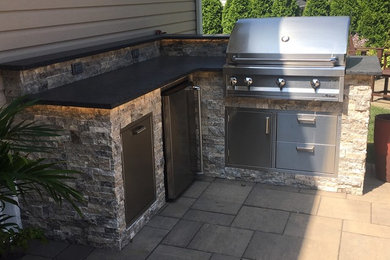 Mid-sized transitional side yard stone patio kitchen photo in New York with no cover