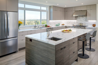 Large contemporary l-shaped open plan kitchen in San Francisco with an undermount sink, flat-panel cabinets, grey cabinets, quartz benchtops, white splashback, stone slab splashback, stainless steel appliances, light hardwood floors, with island and white benchtop.