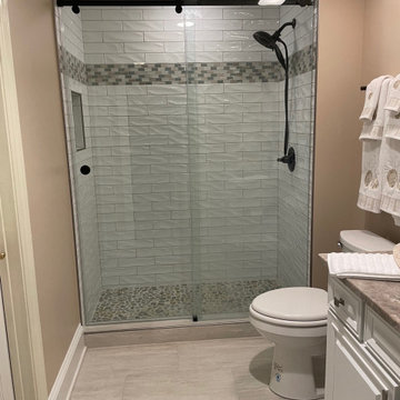 3x12 textured subway tile, with a darker mosaic band and pebble shower floor.