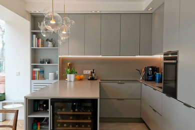 Cette image montre une cuisine design avec un évier posé, des portes de placard grises, un plan de travail en quartz modifié, un électroménager noir, parquet clair et un plan de travail gris.