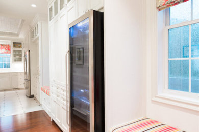 Example of a classic dark wood floor enclosed kitchen design in Calgary with an undermount sink, recessed-panel cabinets, white cabinets, white backsplash, ceramic backsplash, stainless steel appliances and an island