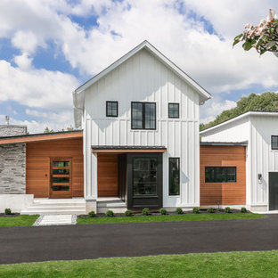 Lantlig inredning av ett mellanstort vitt hus, med två våningar, pulpettak, tak i shingel och blandad fasad