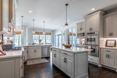 Example of a large transitional u-shaped vinyl floor and brown floor eat-in kitchen design in Atlanta with an undermount sink, raised-panel cabinets, gray cabinets, quartz countertops, white backsplash, subway tile backsplash, stainless steel appliances, an island and white countertops