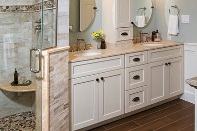 Photo of a large country master bathroom in Philadelphia with flat-panel cabinets, beige cabinets, a claw-foot tub, a corner shower, a two-piece toilet, beige tile, porcelain tile, blue walls, porcelain floors, an undermount sink, limestone benchtops, brown floor and a hinged shower door.