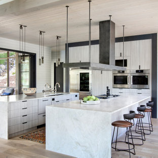 Идея дизайна: п-образная кухня в стиле рустика с врезной раковиной, плоскими фасадами, техникой из нержавеющей стали, светлым паркетным полом, двумя и более островами, кладовкой, серыми фасадами, бежевым полом и серой столешницей