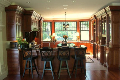 Enclosed kitchen - mid-sized traditional u-shaped medium tone wood floor enclosed kitchen idea in Portland Maine with raised-panel cabinets, medium tone wood cabinets, stainless steel appliances and an island