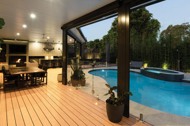 This is an example of a large modern backyard patio in Sydney with an outdoor kitchen, decking and a pergola.